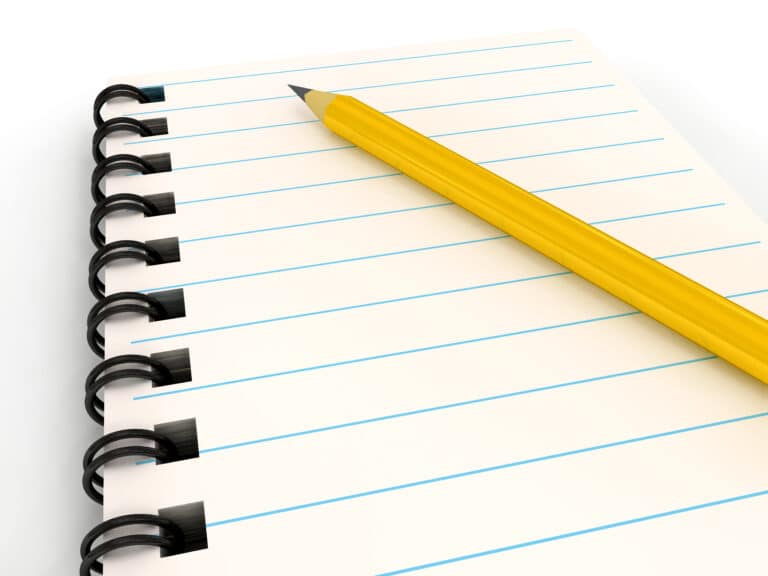 En notatblokk med linjer der det ligger en blyant oppå.