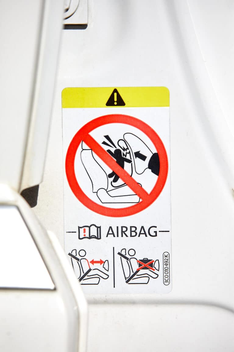 Illustrasjon som viser at bakovervendt bilstol ikke må stå foran en aktiv airbag.