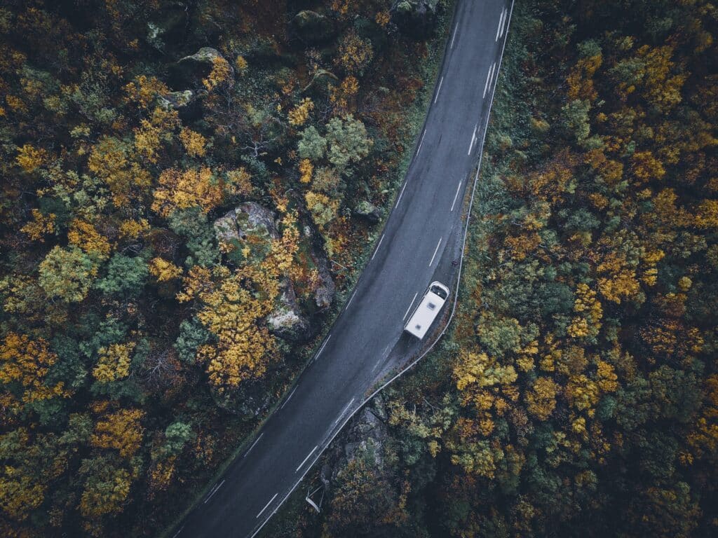 Bildet tatt med drone over smal vei. På den smale veien står en bil parkert i en møtelomme.
