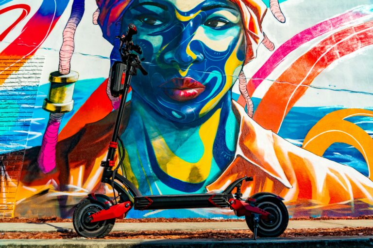 Bilde av elsparkesykkel foran en vegg med streetart.