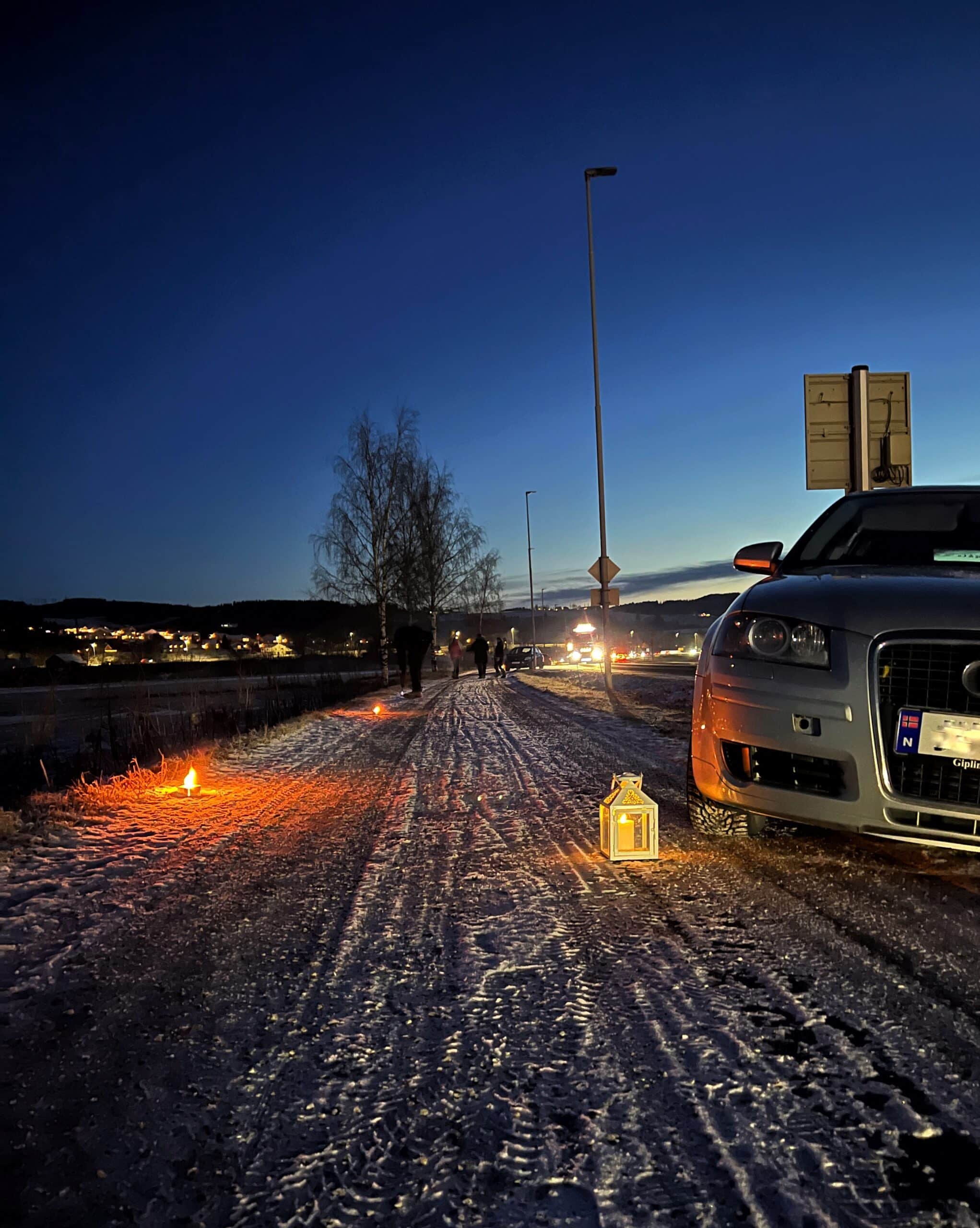 Bil i snøen langs veikanten med en lyslykt foran.