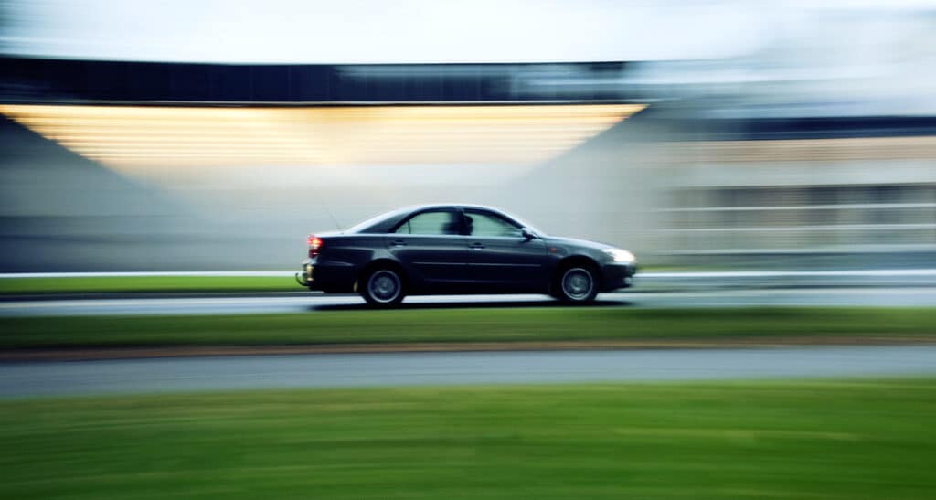 Bilde av en bil på en vei med gress i front. Effektene i bildet skal tilsi at bilen er i stor fart.