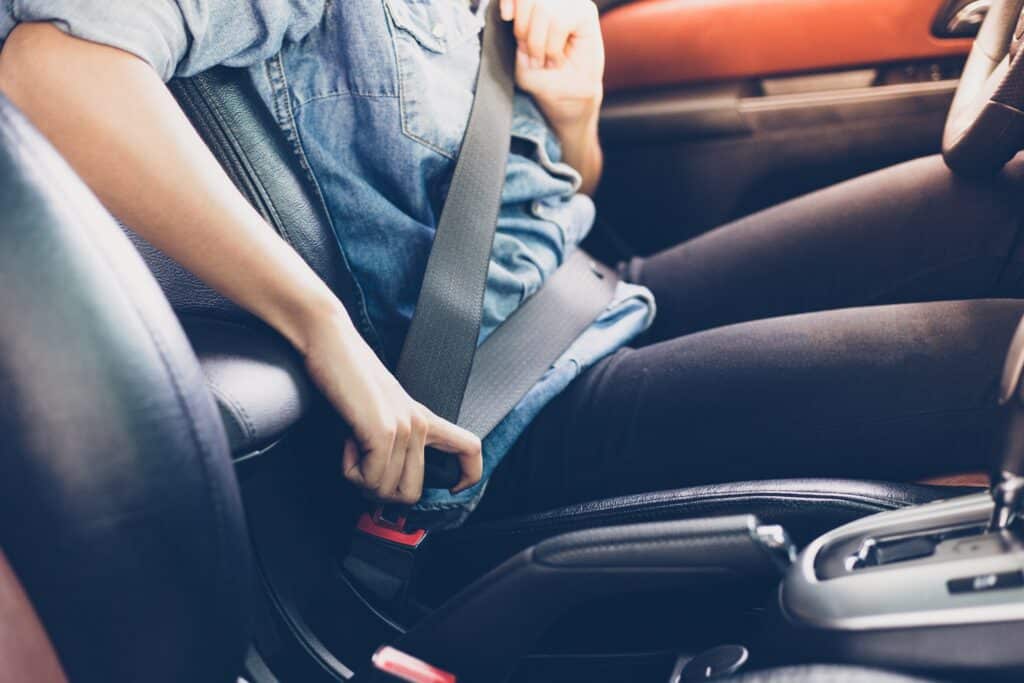 Bilde av en person som fester setebeltet i festet for setebelstet i bilen.