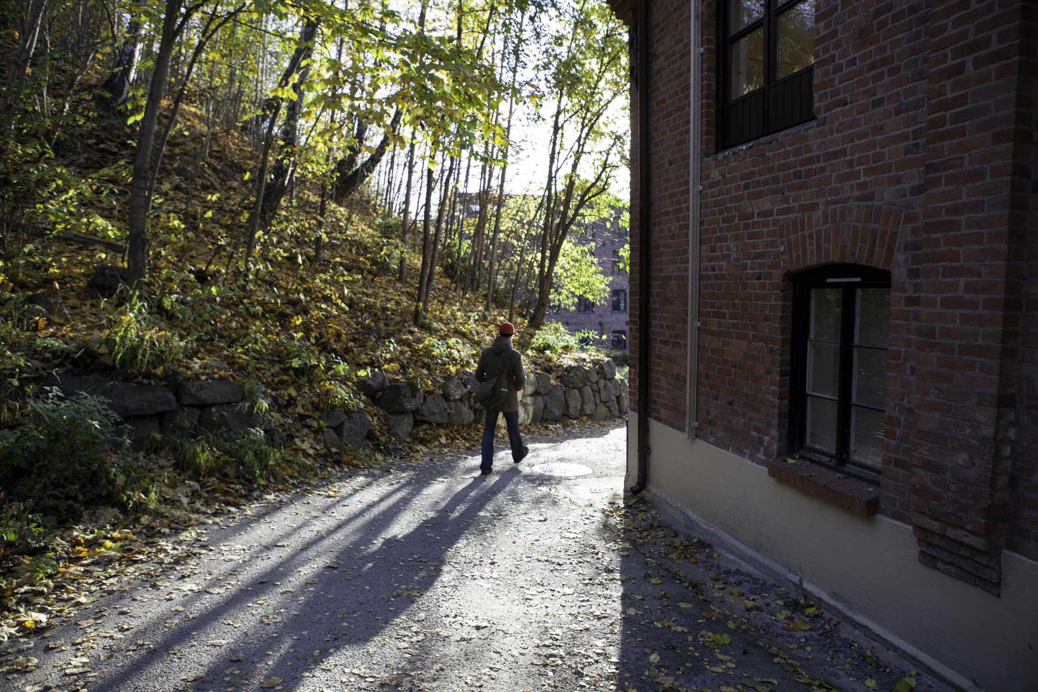 Person på tur på grusvei forbi et mursteinsbygg