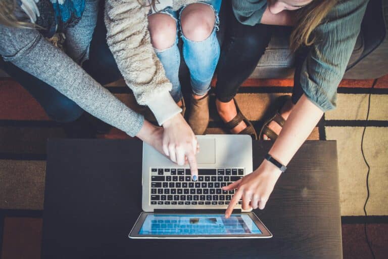 Bilde av personer ovenfra som peker og trykker på tastaturet til en laptop.