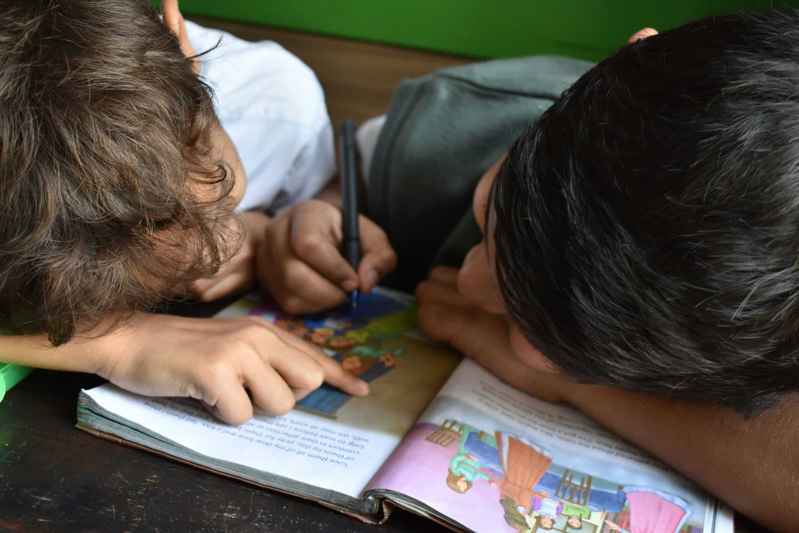 To barn som sitter og fargelegger i en bok sammen.