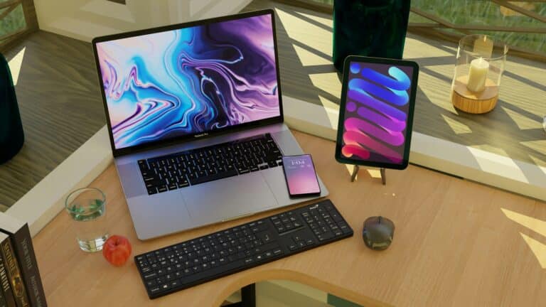En mac, et tastatur og en pad på et skrivebord.