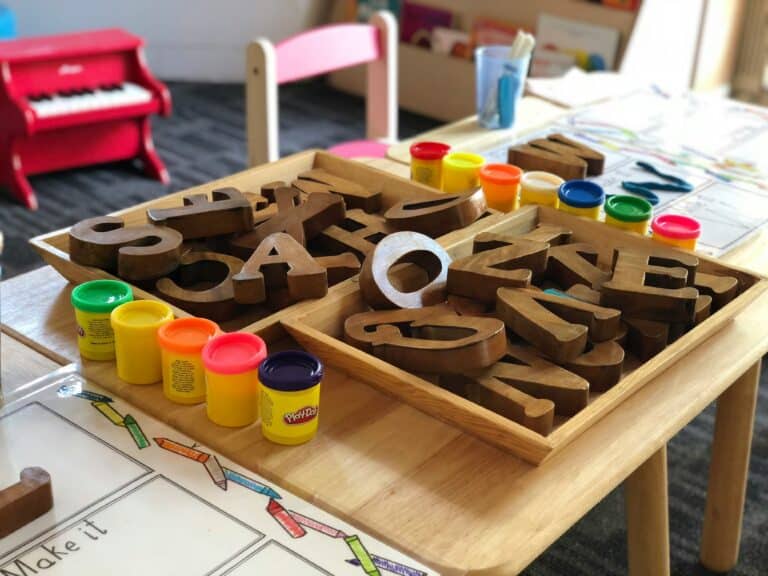 Bokstavklosser og Playdohbokser på et bord i barnehage.