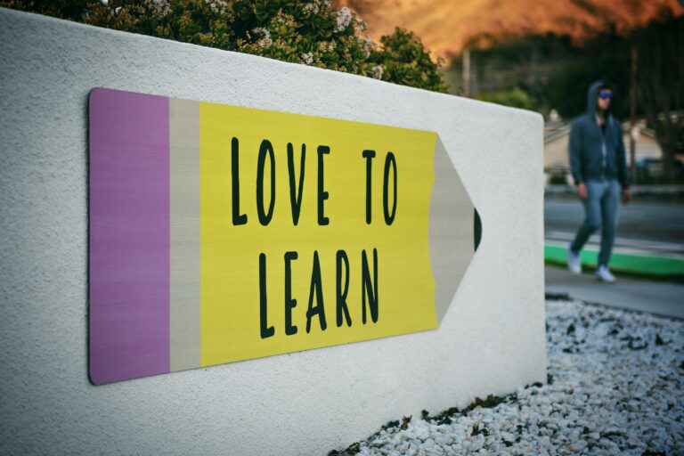 Et skilt på en murvegg som ser ut som en blyant. Det står "Love to learn".