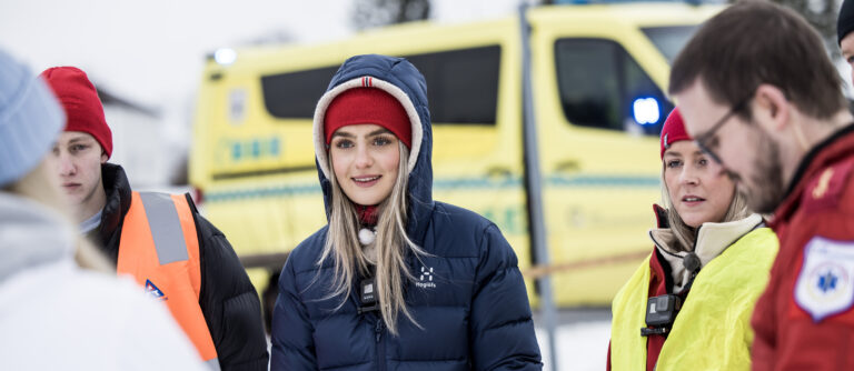 Ungdom med vinterklær foran en ambulanse.