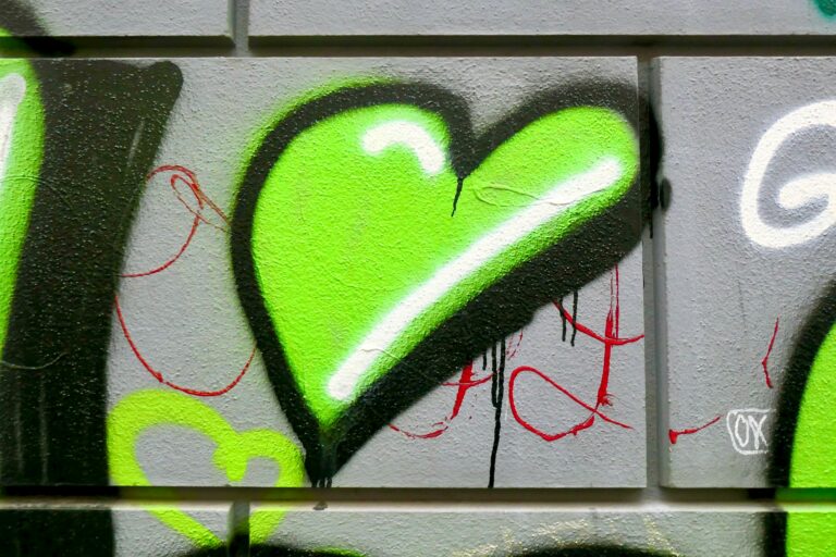Grafittihjerte i grønt på steinvegg.